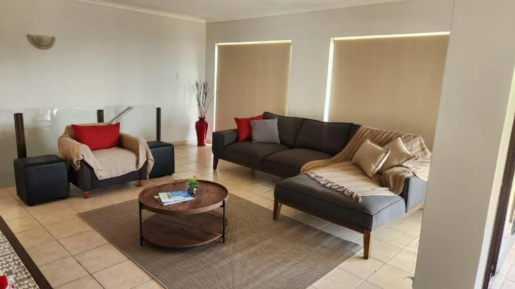 Modern lounge with black sofas, red cushions, wooden coffee table