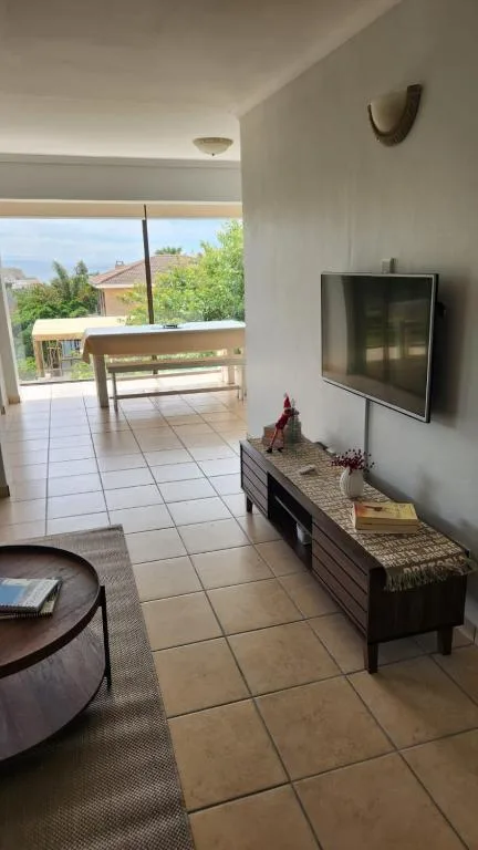 Spacious lounge with TV, deck views, and natural light