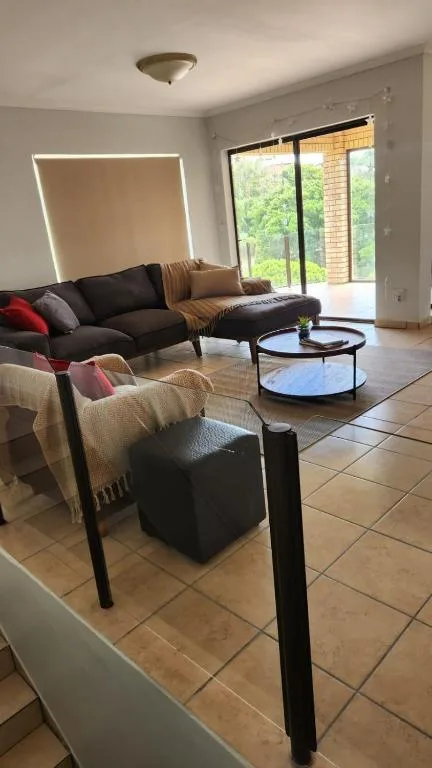 Modern living room with black sofa, armchair, and glass coffee table