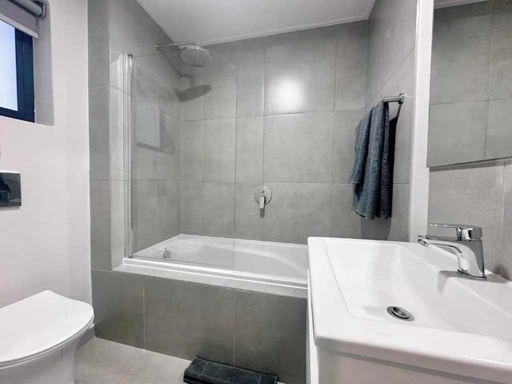 Modern bathroom with glass shower enclosure, white sink, and toilet