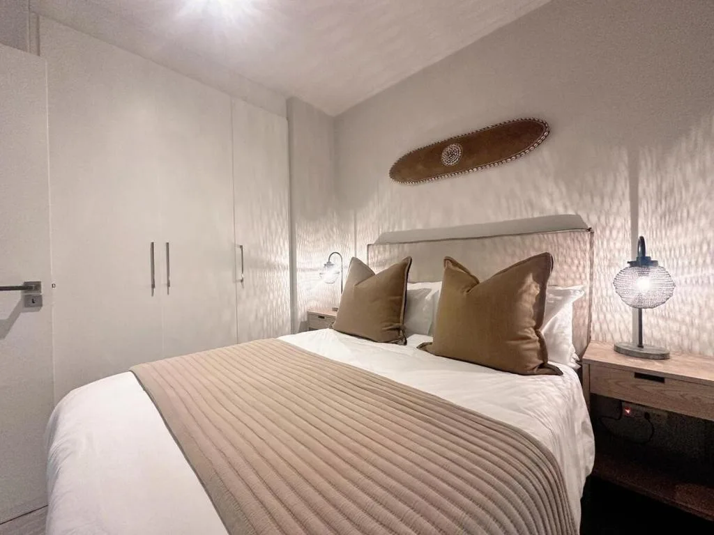 Modern bedroom with queen bed, gold pillows, and contemporary wall art