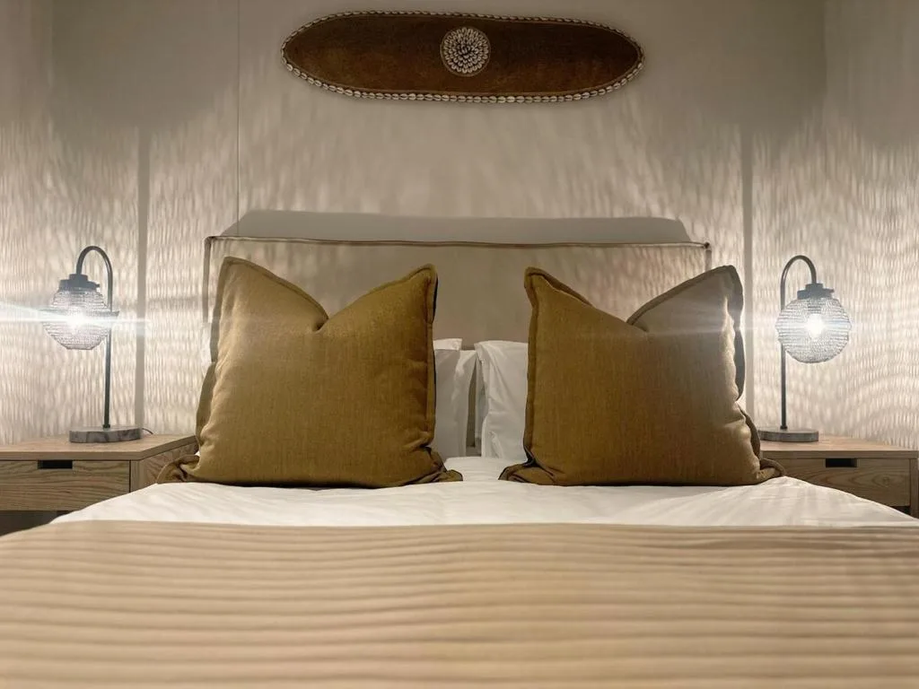 Modern bedroom with bed, gold cushions, and elegant pendant lighting fixtures
