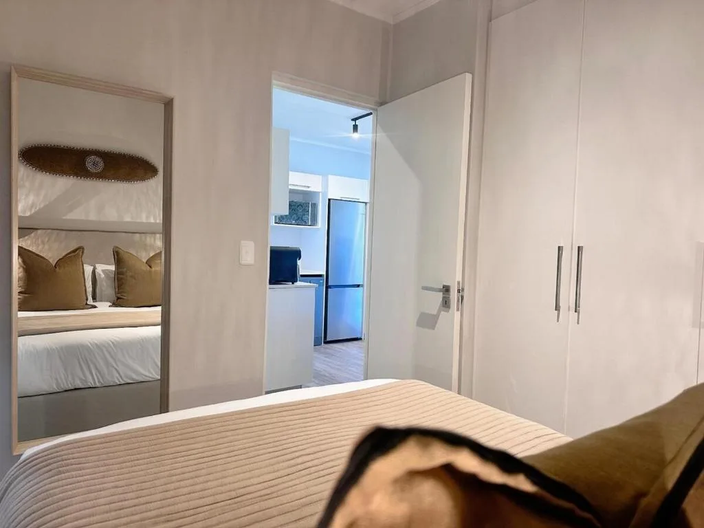 Modern bedroom with mirrored wardrobe and view to open-plan living area
