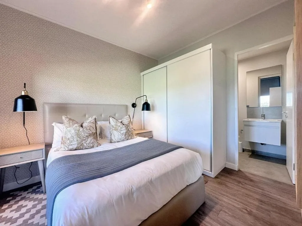 Modern bedroom with queen bed, patterned wallpaper, and ensuite bathroom access