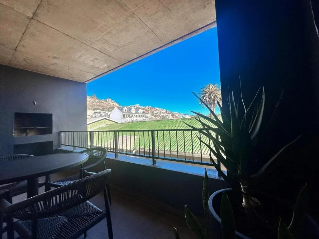 Covered balcony with dining table overlooking green valley and mountains