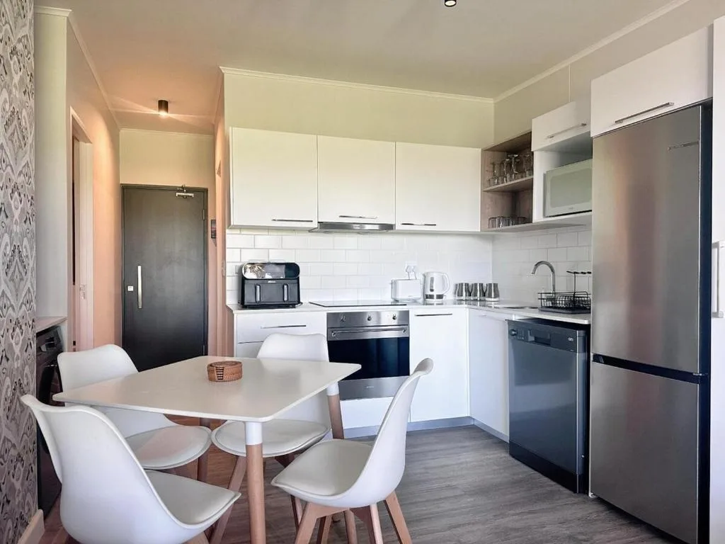 Modern kitchen with white cabinetry, stainless steel appliances, and dining table