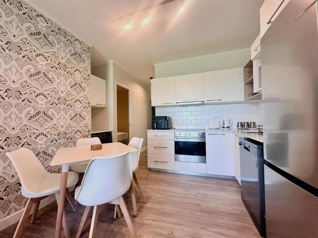 Modern white kitchen with dining table and patterned feature wall