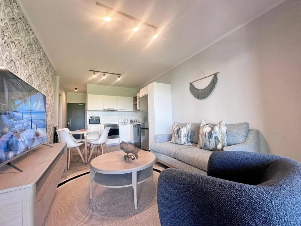 Modern lounge with gray sofa, armchair, round coffee table, and TV