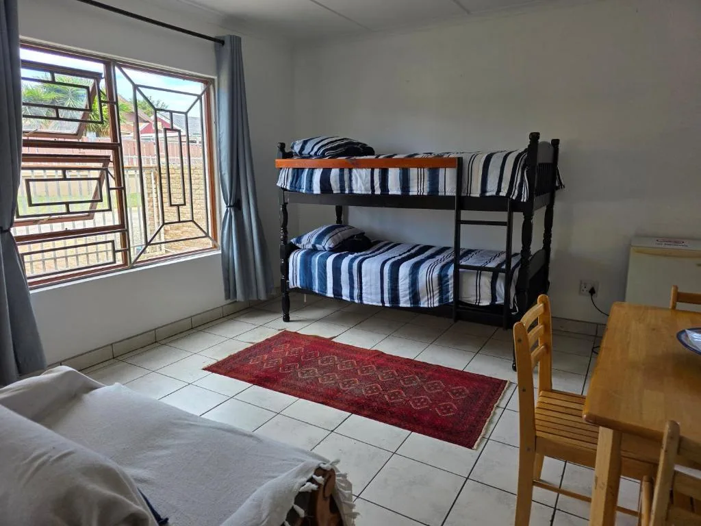 Bright bedroom with bunk beds, striped bedding, and large windows overlooking garden