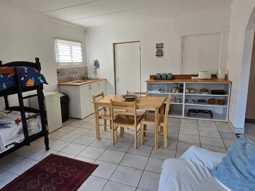Open-plan studio with dining table, kitchenette, beds and storage shelving