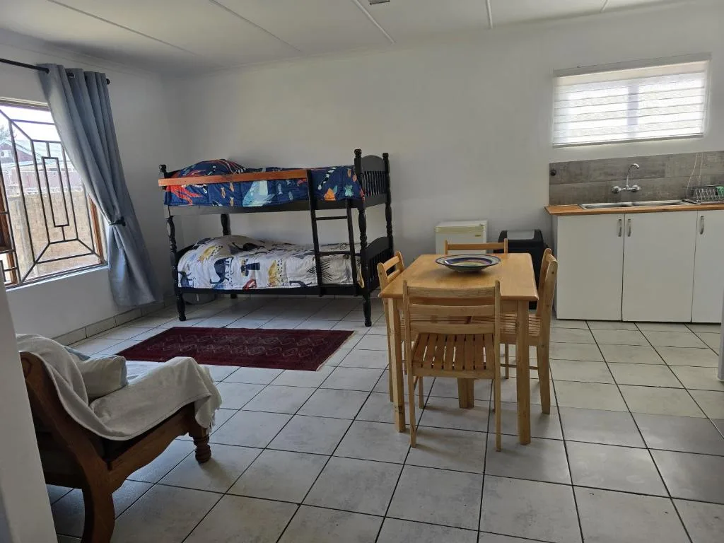 Open-plan studio showing bunk beds, dining table, kitchenette and seating area