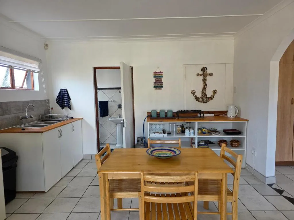 Open-plan kitchen and dining area with wooden table and anchor wall decor