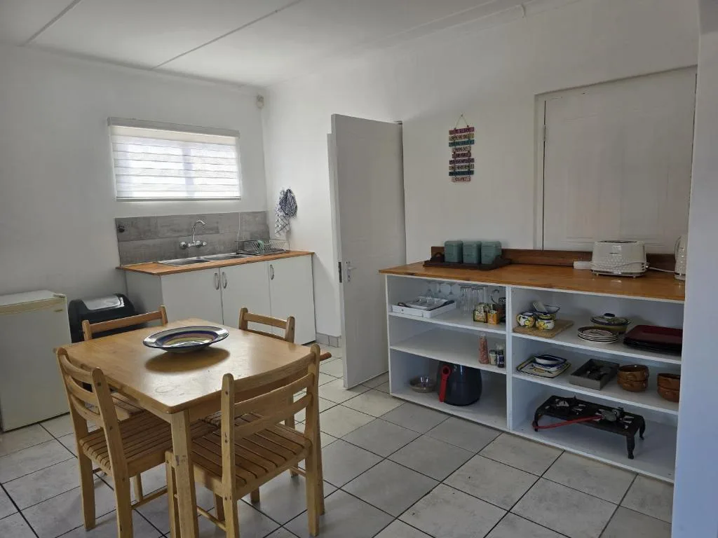 Dining area with wooden table, chairs, kitchenette, and storage shelves