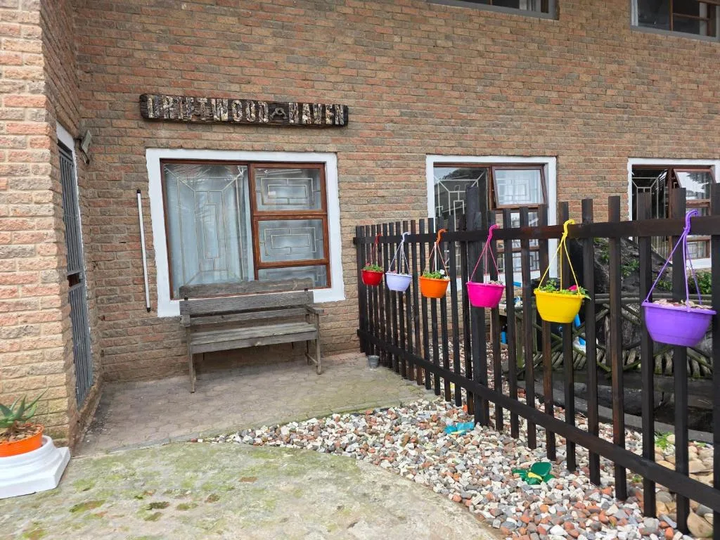 Brick building entrance with wooden bench and colorful hanging planters