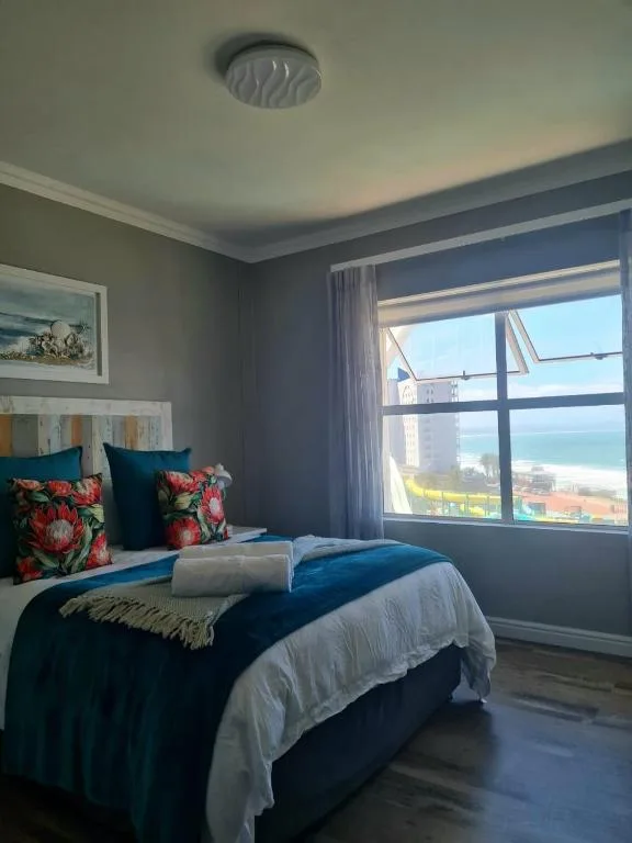 Bright bedroom with ocean view through large windows and colorful pillows