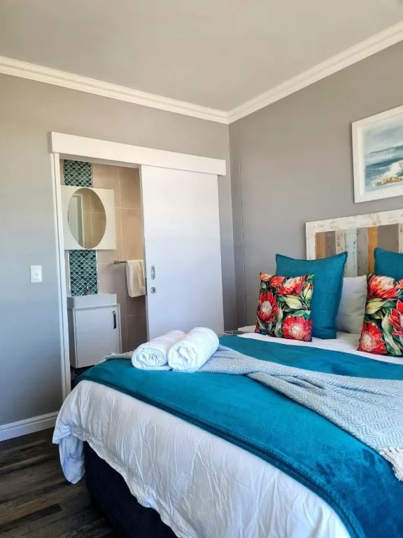 Bright bedroom with queen bed, colorful pillows, and en-suite bathroom entrance