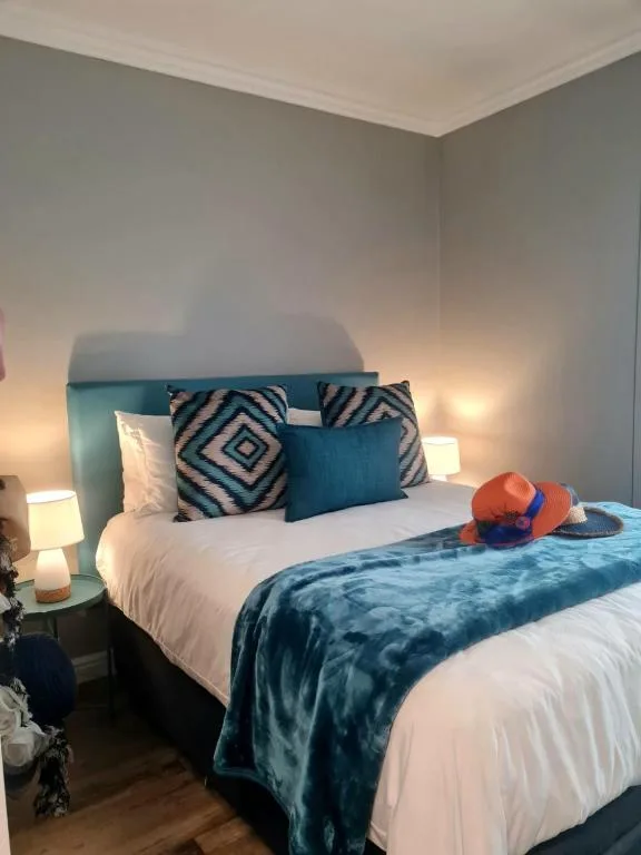 Modern bedroom with teal headboard, patterned pillows, and bedside lamps