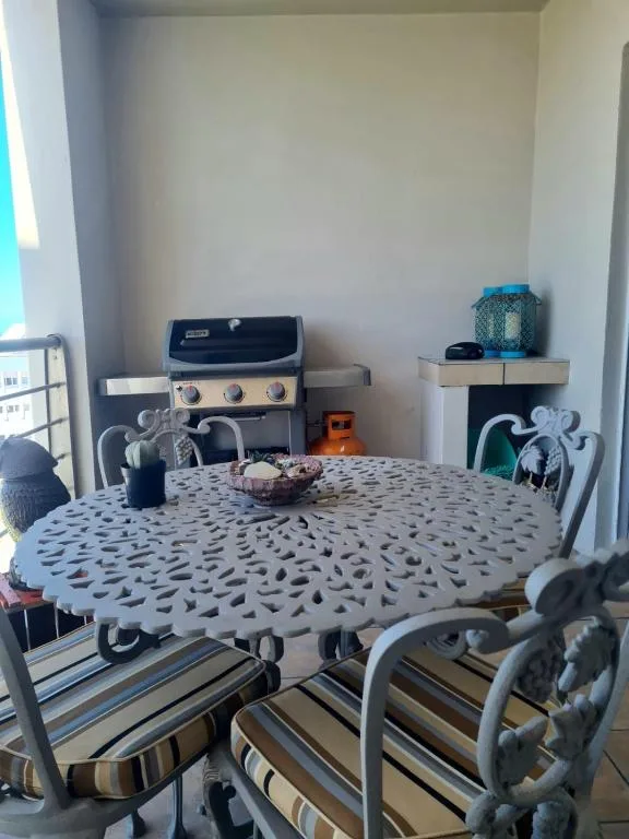 Outdoor patio area with round dining table and gas braai grill