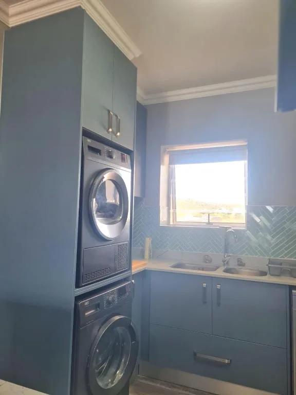 Modern laundry room with stacked washer dryer and blue cabinetry