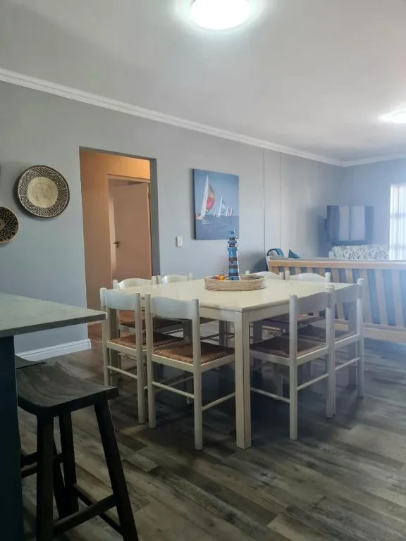 Bright dining area with wooden table, rush-seat chairs, coastal artwork