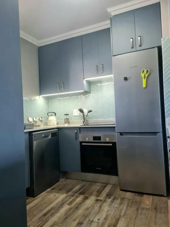 Modern kitchen with blue cabinetry, stainless steel appliances, and herringbone backtile