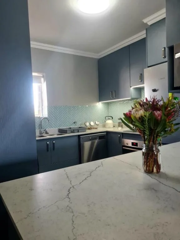 Modern kitchen with dark cabinetry, marble countertop, and fresh flowers