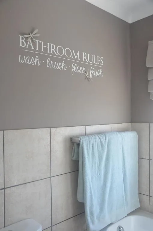 Bathroom wall with decorative 'Bathroom Rules' text and towel rack