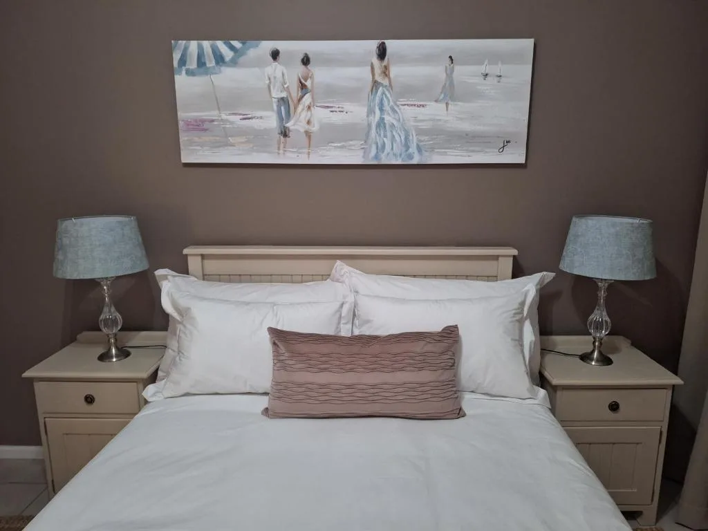 Master bedroom with queen bed, white linens, and beach-themed wall art above