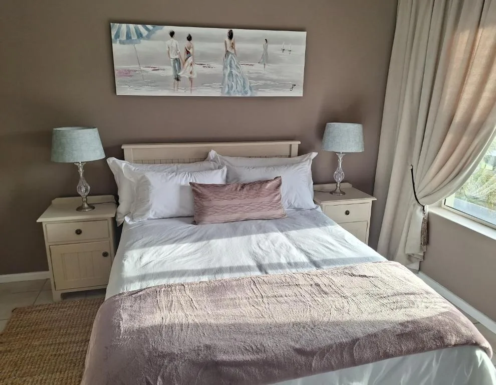 Spacious bedroom with queen bed, coastal artwork, and elegant furnishings