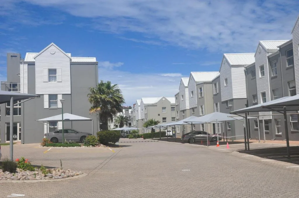 Modern white townhouses with metal roofs arranged around paved courtyard