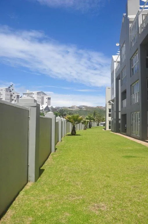 Manicured green lawn with palm tree, modern buildings and mountain views