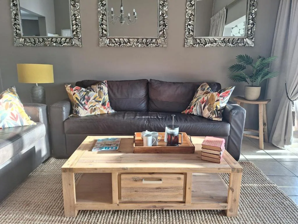 Contemporary lounge with dark leather sofa, decorative mirrors, and wooden coffee table