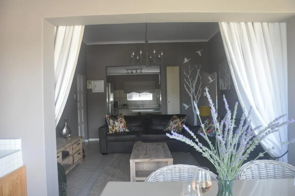 Modern lounge with black sofa, dark accent wall, and kitchen visible beyond