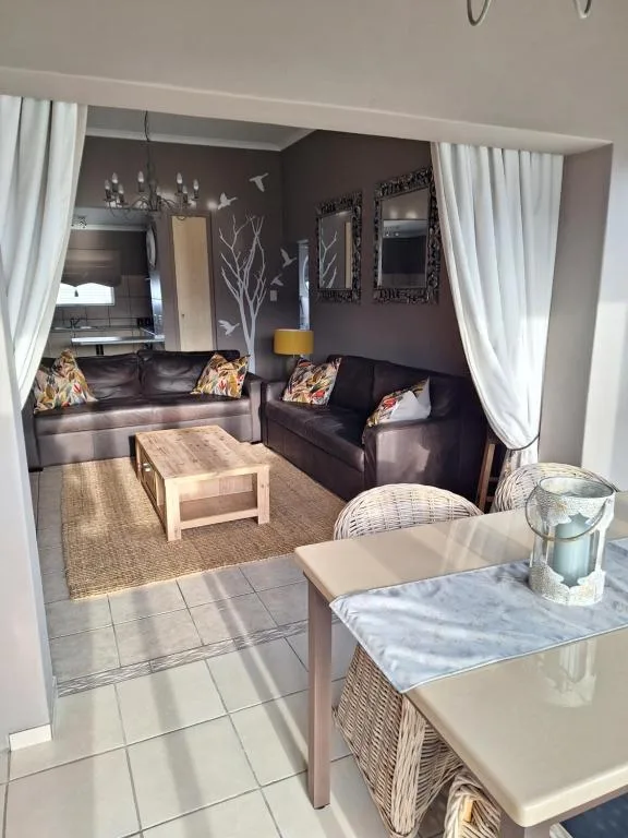 Modern lounge with black leather sofas, wooden coffee table, and wall art