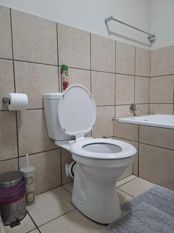 Clean bathroom with white toilet, tiled walls, and roll holder