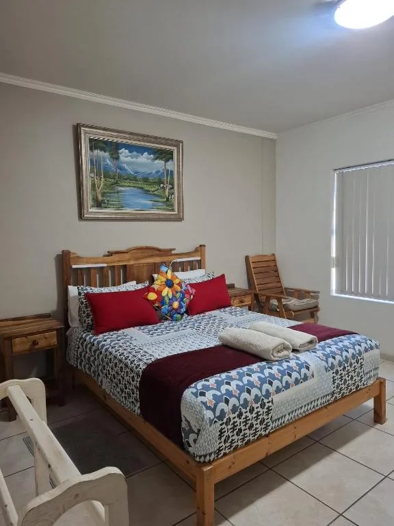 Wooden bed with red pillows and patterned bedding in bright bedroom