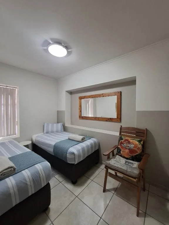 Twin bedroom with striped bedding, wooden mirror, and modern ceiling light