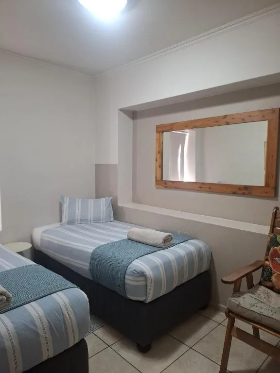 Twin bedroom with striped bedding, wooden mirror, and neutral décor
