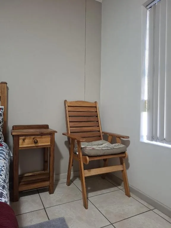 Wooden chair with cushion beside nightstand in bright bedroom