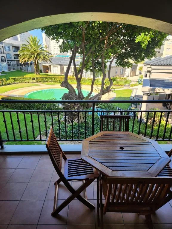 Shaded balcony with dining table overlooking lush gardens and pool