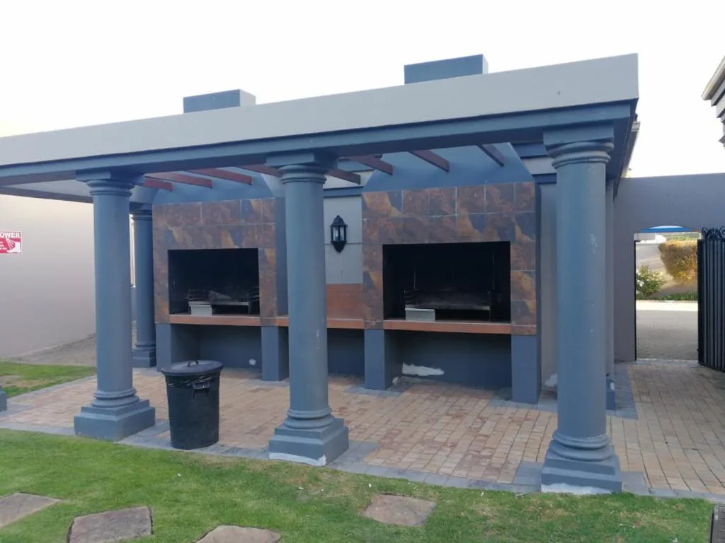 Covered outdoor braai area with twin built-in fireplaces and seating