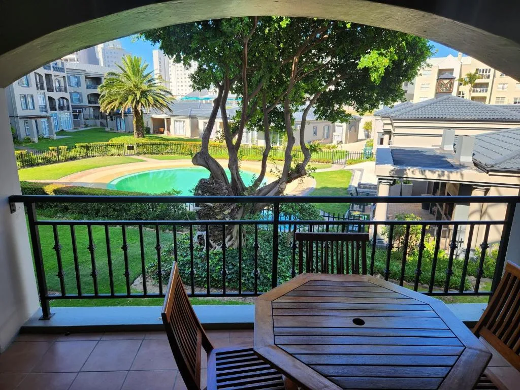 Shaded balcony with wooden furniture overlooking pool and gardens