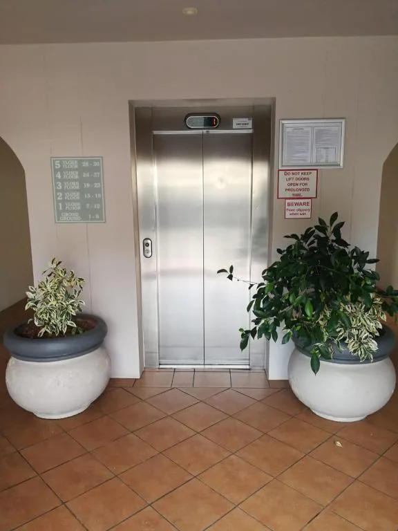 Elevator entrance with potted plants and building directory signage