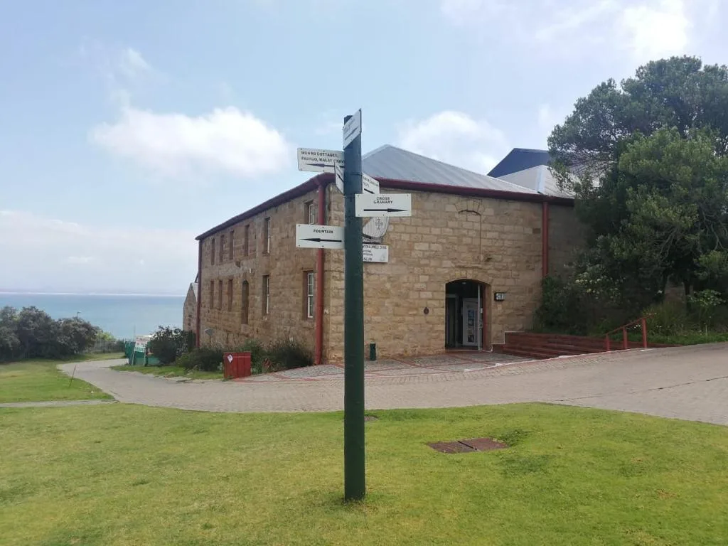 Historic stone building with red trim and ocean view in background