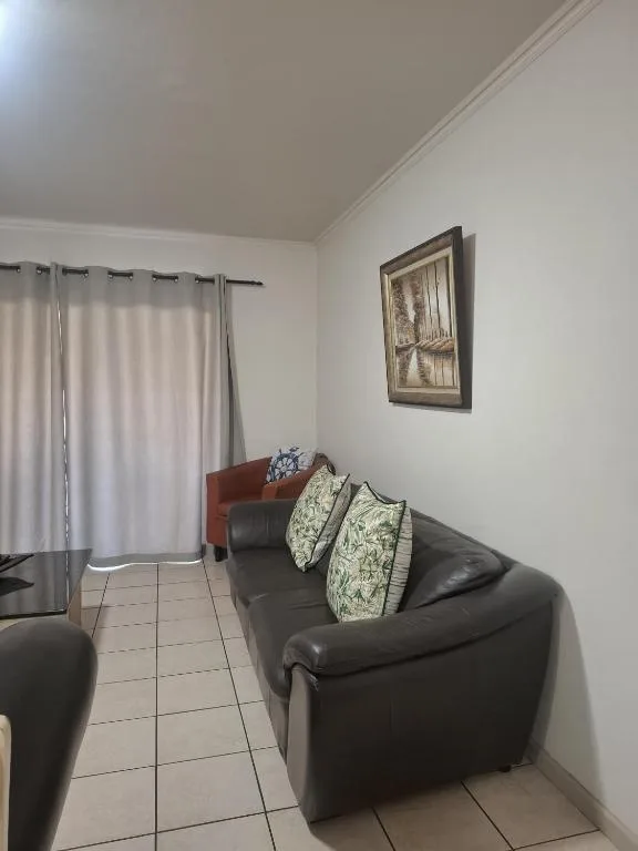 Comfortable lounge area with black leather sofa and decorative pillows