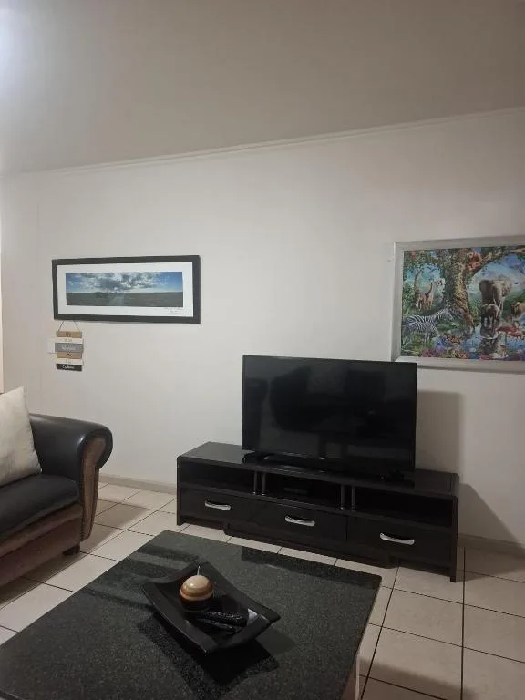 Living room with TV, leather armchair, and framed wildlife artwork on walls