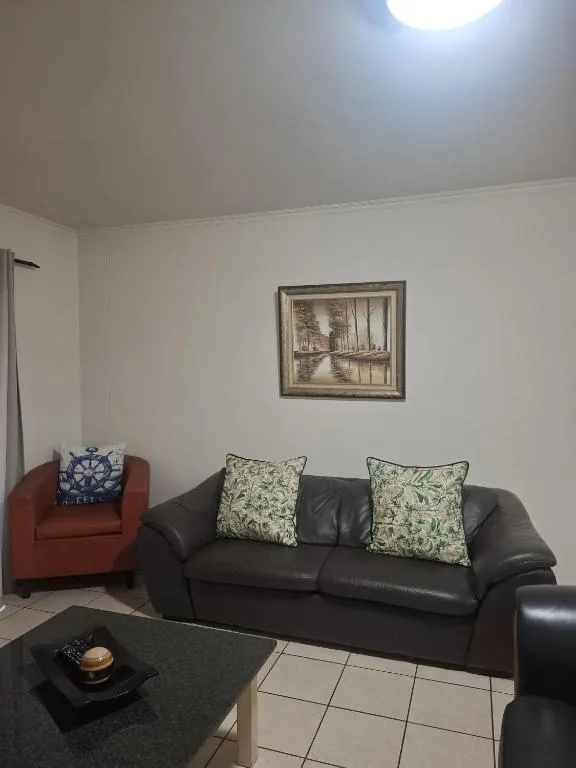 Modern lounge with black leather sofa, red armchair, and framed wall art
