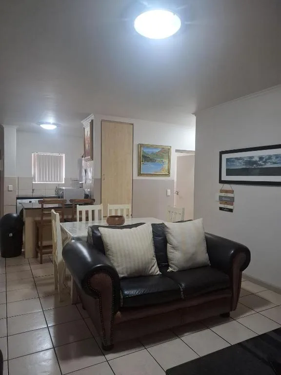 Open-plan living area with black leather sofa and cream cushions