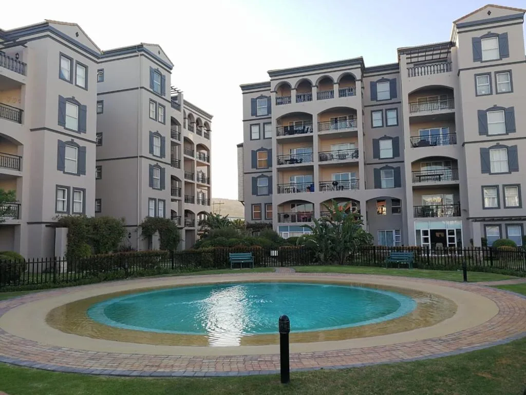 Circular swimming pool surrounded by brick paving and manicured lawns
