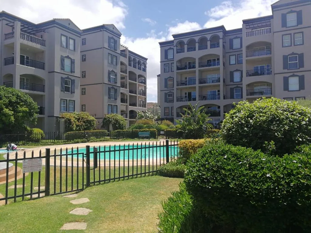 Turquoise swimming pool fenced with landscaped gardens and apartment buildings